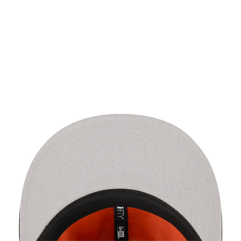 White baseball cap with black brim edge and orange interior lining.