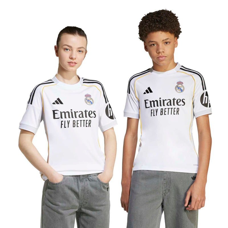 Youth Real Madrid home replica jersey on model, white with Emirates Fly Better print