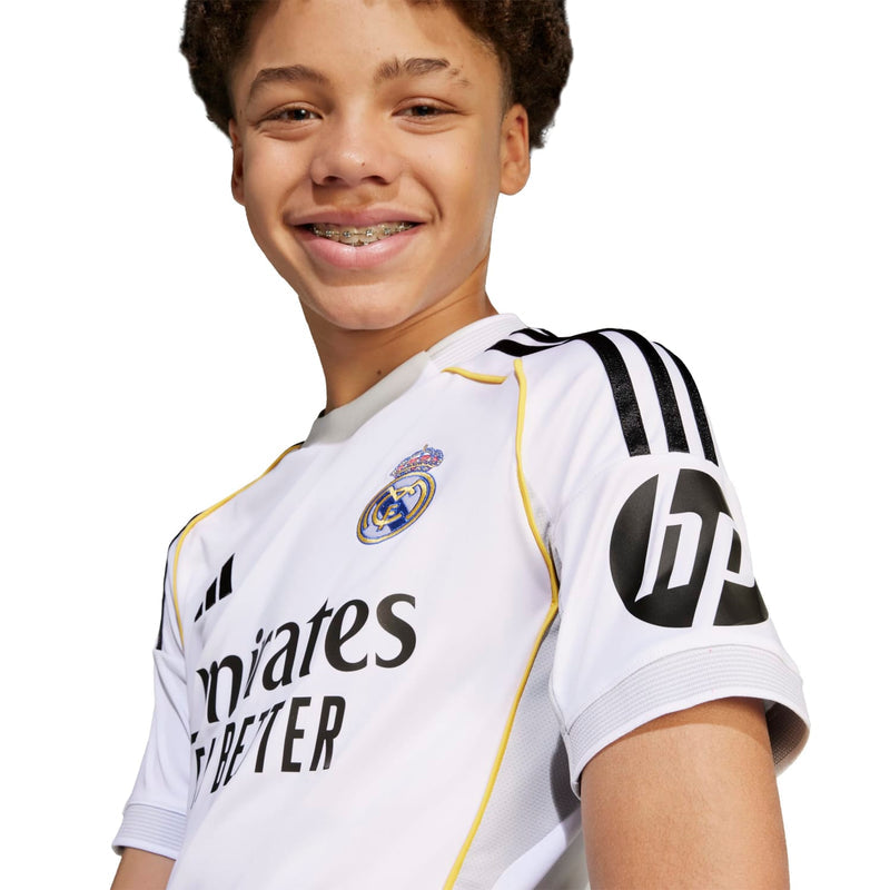Youth Real Madrid home replica jersey close-up, gold-trim sleeve stripes and club crest