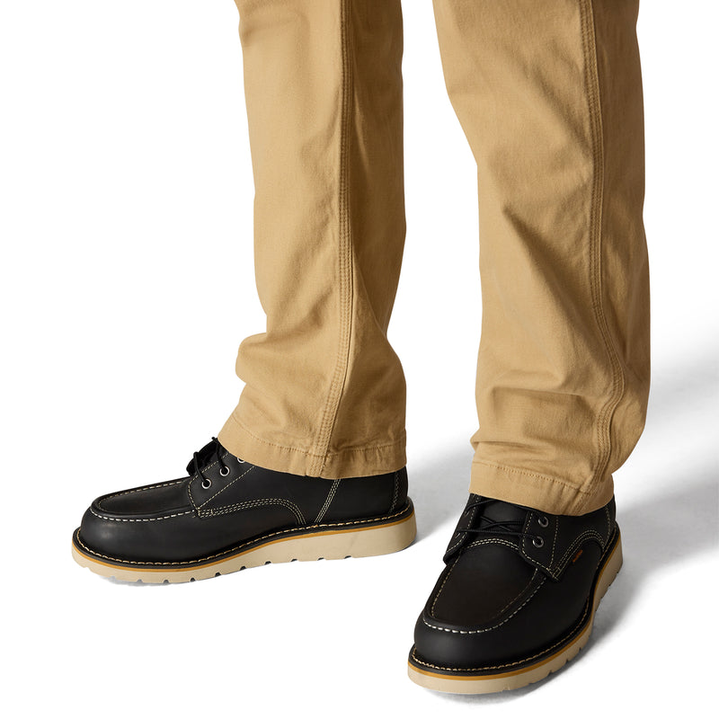 Dark khaki dungaree pants cuffed at hem with black leather-style shoes
