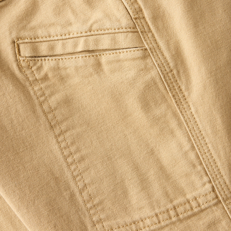 Close-up of dark khaki dungaree fabric with reinforced stitching and pocket edge
