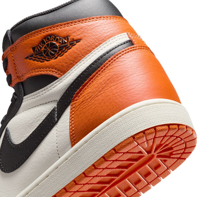 Men's high-top sneakers close-up of Air Jordan wing logo on orange leather, outsole.