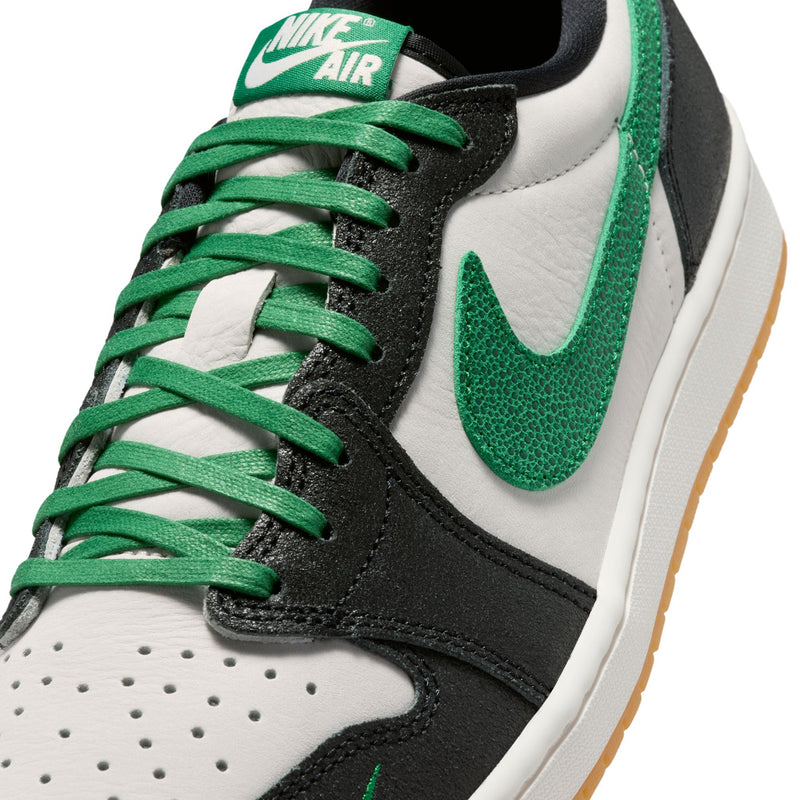 Close-up of black, white, and green low-top sneakers with perforated toe and green laces.