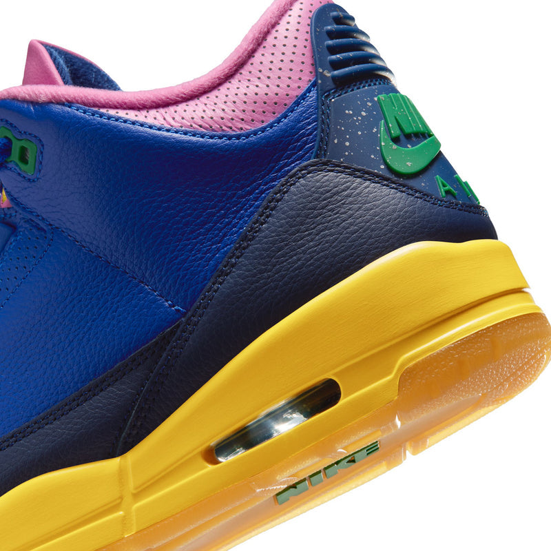 Close-up of men's retro high-top sneaker: navy panel, blue leather, yellow air-cushion sole edge.