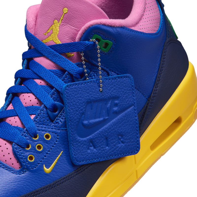 Close-up of men's retro high-top sneaker side: blue leather, pink lace base, hanging charm detail.