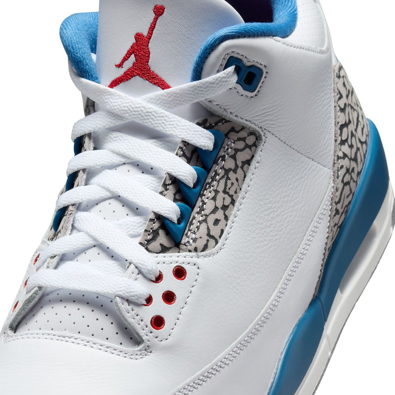 Men's white sneaker close-up with Jumpman tongue, laces, and blue heel tab