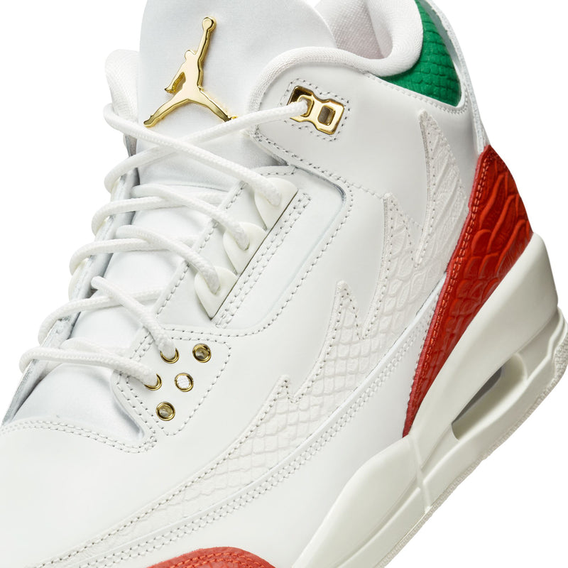 Close-up of white retro sneakers with gold lace eyelets and red textured panel