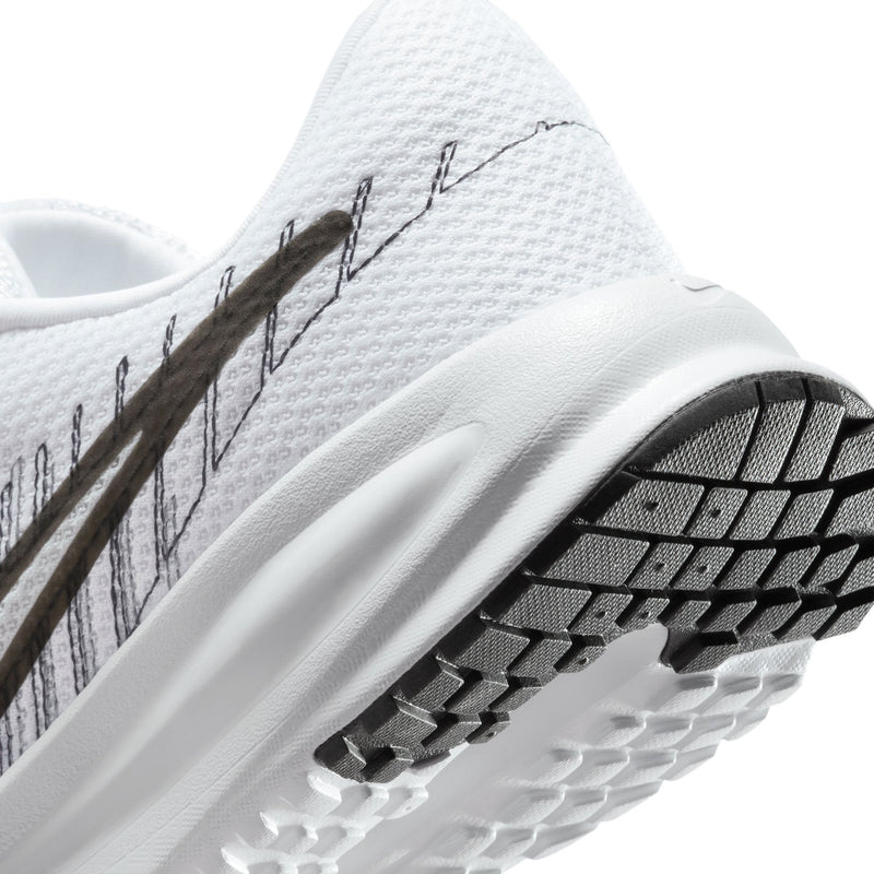 Women's running shoe sole and upper close-up with black traction pods on tread