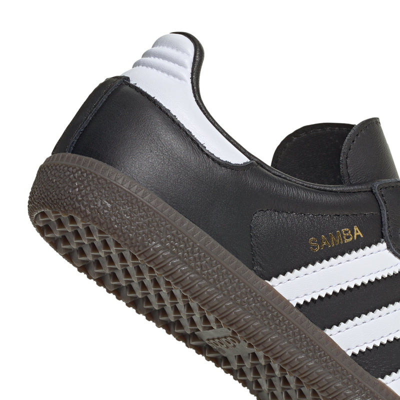 Kids retro sneakers side close-up, black upper with white stripes and textured gum sole.