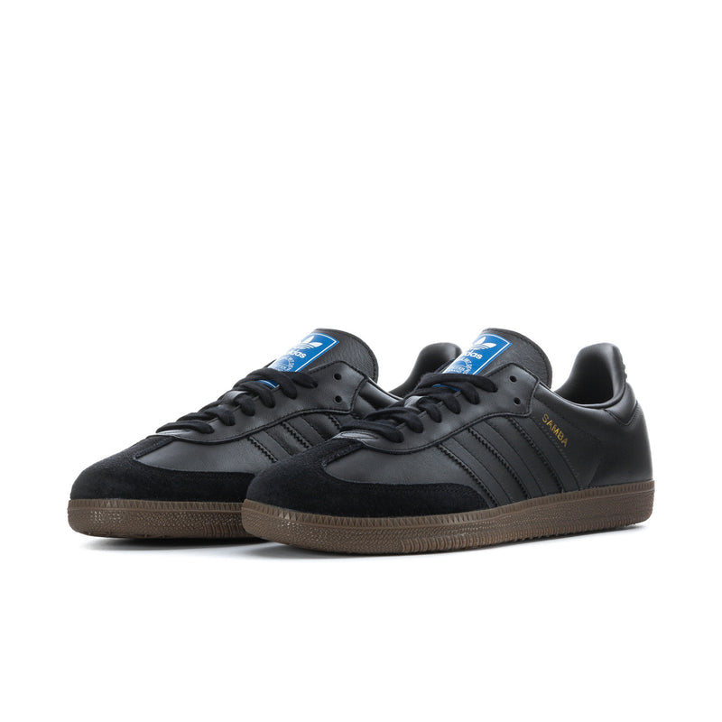 Pair of black adidas Samba OG sneakers with blue tongue details and gum soles
