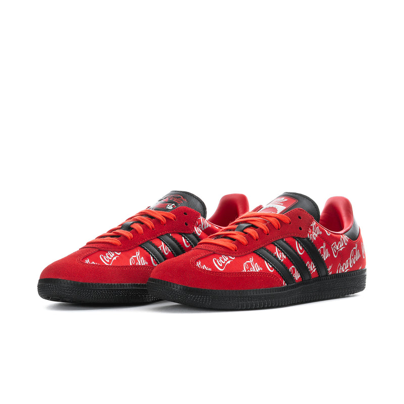 Red and black low-top sneakers with Coca-Cola script uppers and orange lace