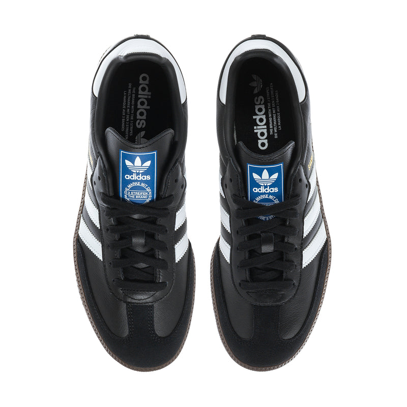 Black adidas Samba OG sneakers with blue adidas tongue label and white side stripes.