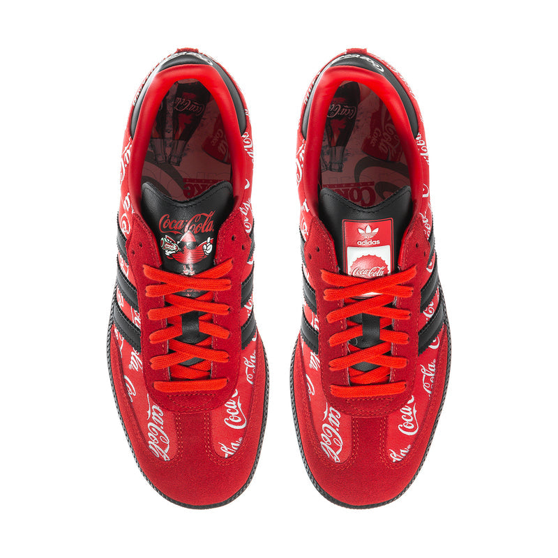 Red low-top sneakers with Coca-Cola script lining, red laces, and black tongue patch