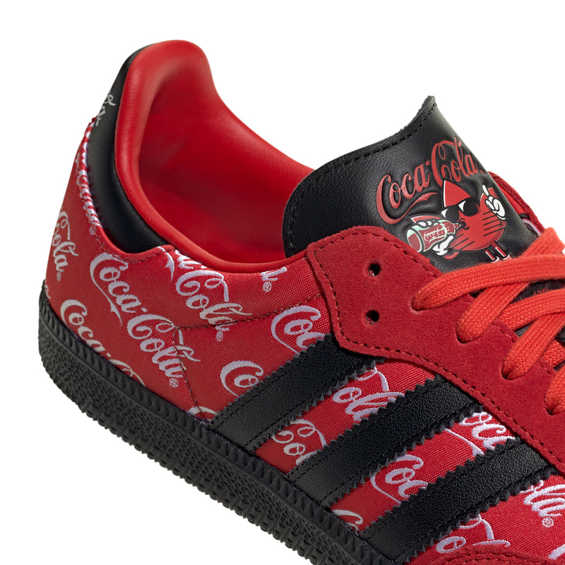 Close-up of red and black low-top sneakers with Coca-Cola script and red laces