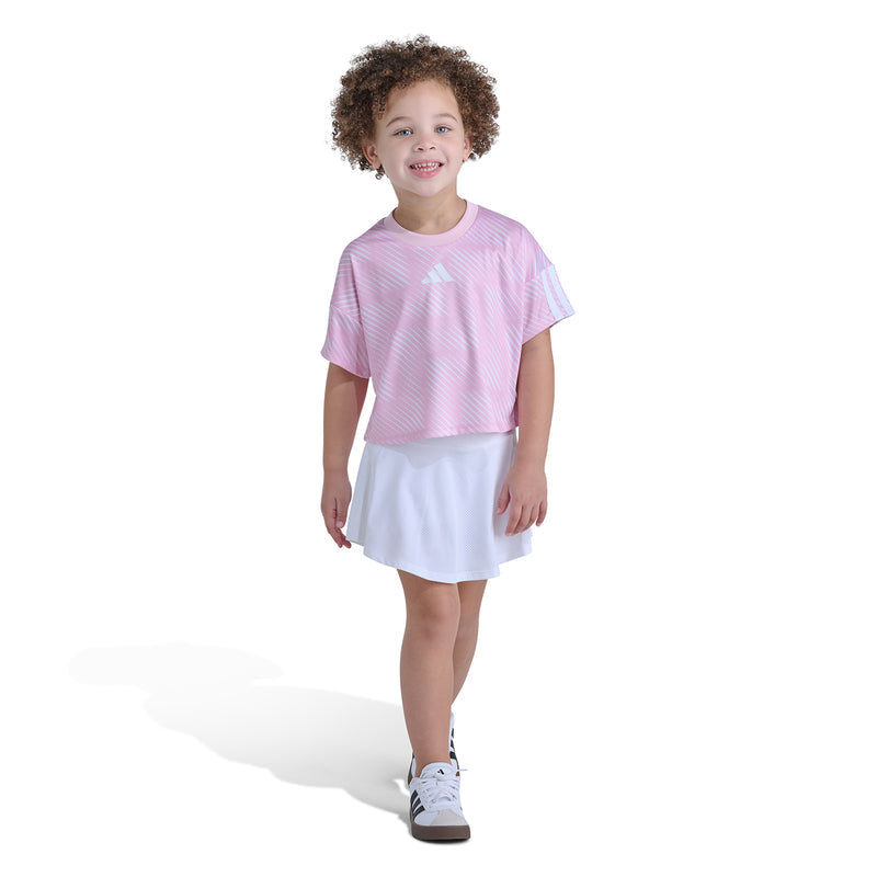 Kids pink striped jersey top paired with white skort, relaxed standing pose