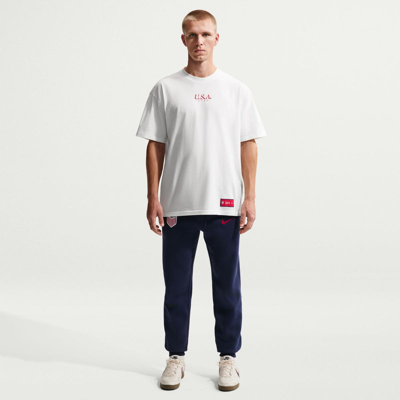Men's sail soccer tee worn with dark navy pants; chest U.S.A. print and red hem tag