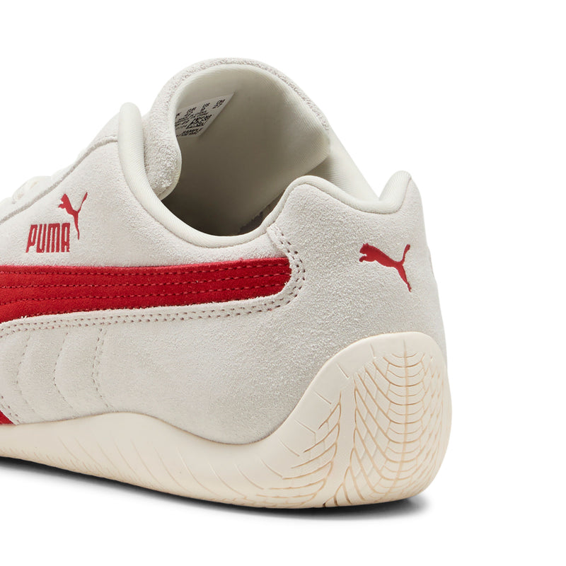 Women's Puma sneaker heel close-up; off-white suede with red stripe and textured sole