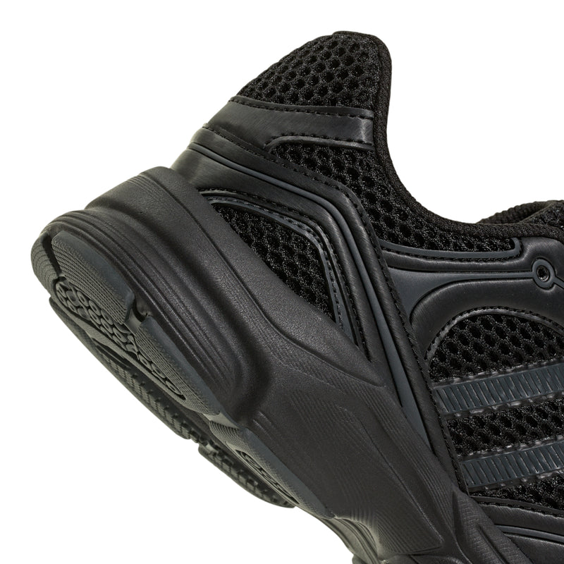 Youth black sneaker side close-up showing ventilation mesh and molded heel