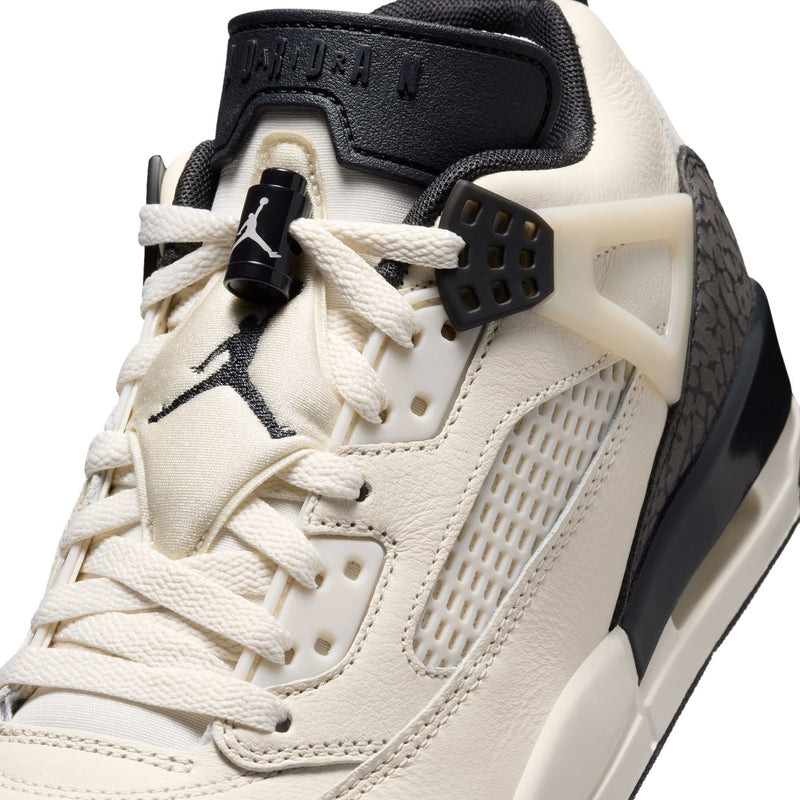 Close-up of women’s cream sneaker upper with lace loops, textured panel, and logos.