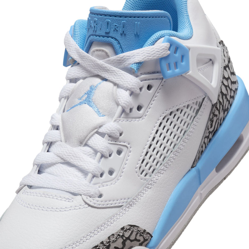 Close-up youth low-top sneakers: white laces, mesh panel, blue logo, speckled overlay