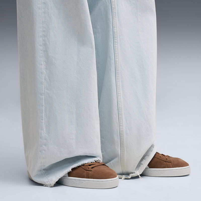 Brown suede sneakers with white rubber sole, worn with light blue jeans
