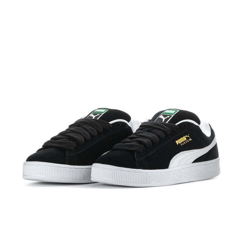 Pair of black suede Puma sneakers with white stripes and thick white platform sole