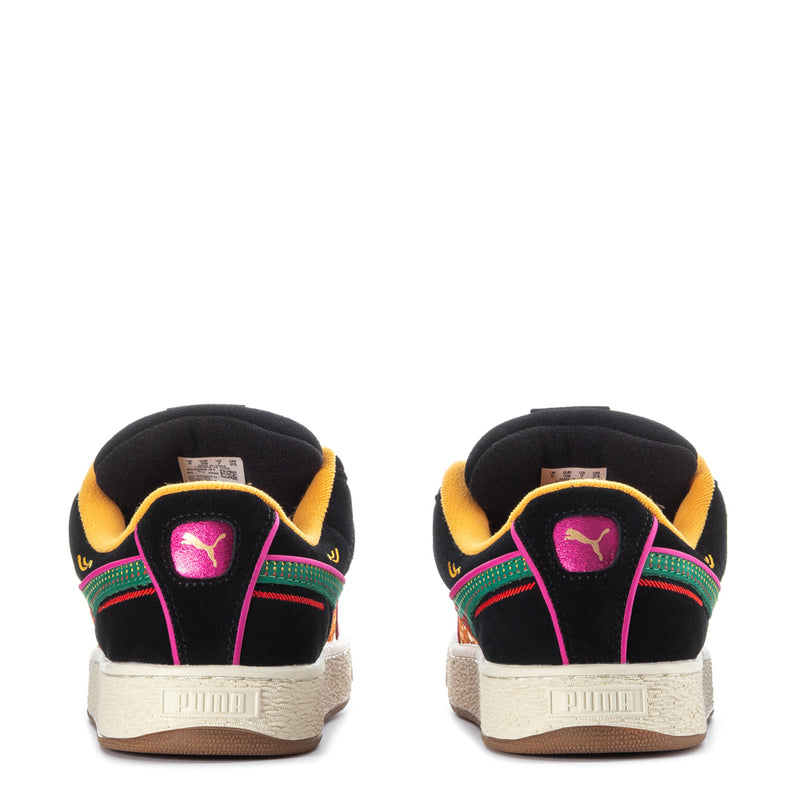 Black suede sneakers with purple heel logo, yellow collar, and colorful stripe trim.