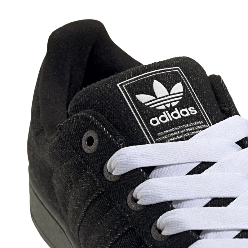 Close-up of black adidas sneakers with white laces and tongue badge logo