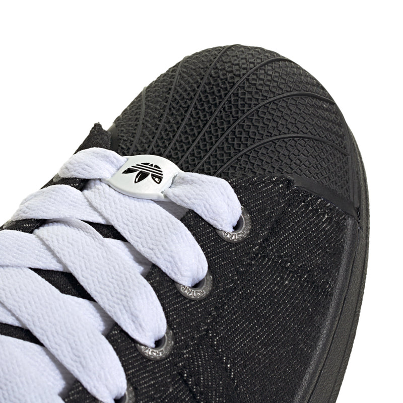 Close-up of black sneaker side with white laces and textured fabric upper