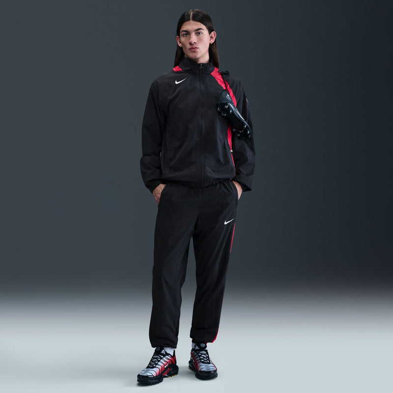 Men's black track pants with red side panels and Nike swoosh; tapered cuffs