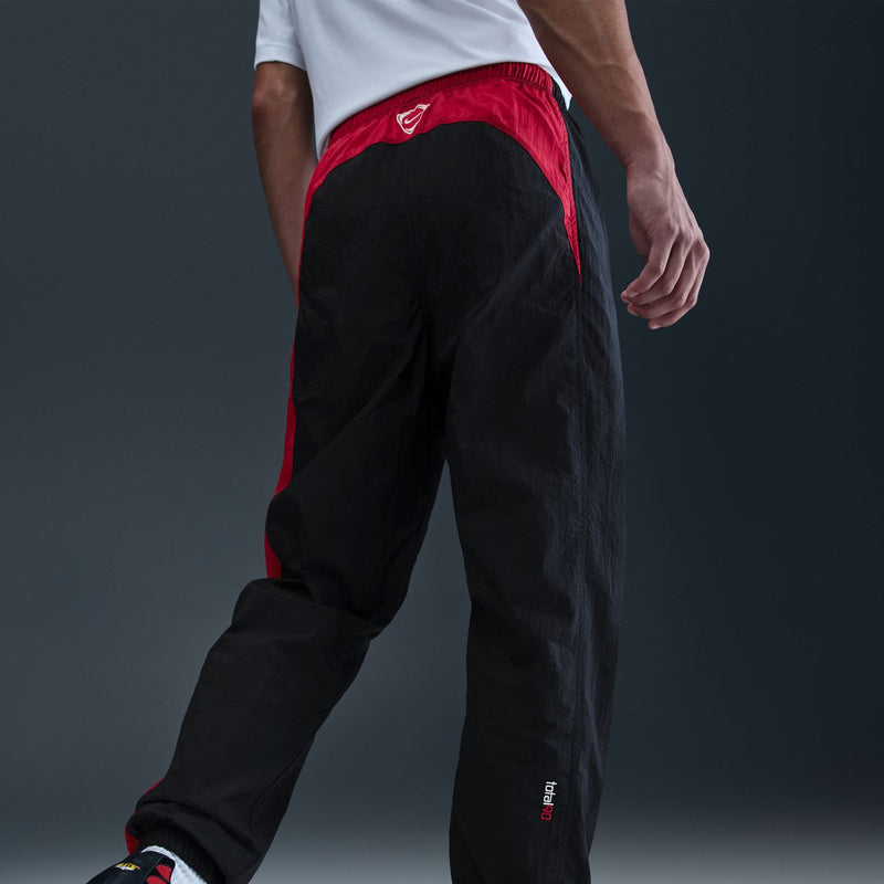 Men's black track pants with red waistband lining and Nike swoosh on thigh
