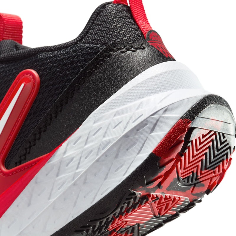 Kids' shoe side view with black upper, red accents, and white traction outsole tread.