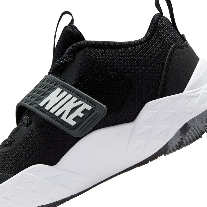 Youth Nike sneaker close-up, black upper with NIKE logo strap and white outsole