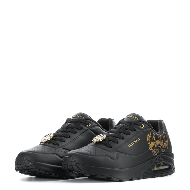 Pair of men's SKECHERS Uno sneakers, black with gold skull patches and lace accents