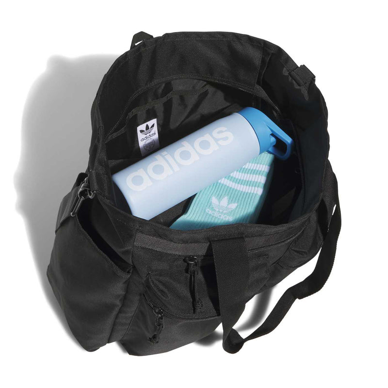 Black open-top utility tote holding an adidas canister and a blue-and-teal item inside.