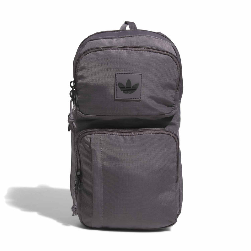 Grey utility sling bag with front zip pockets and logo patch