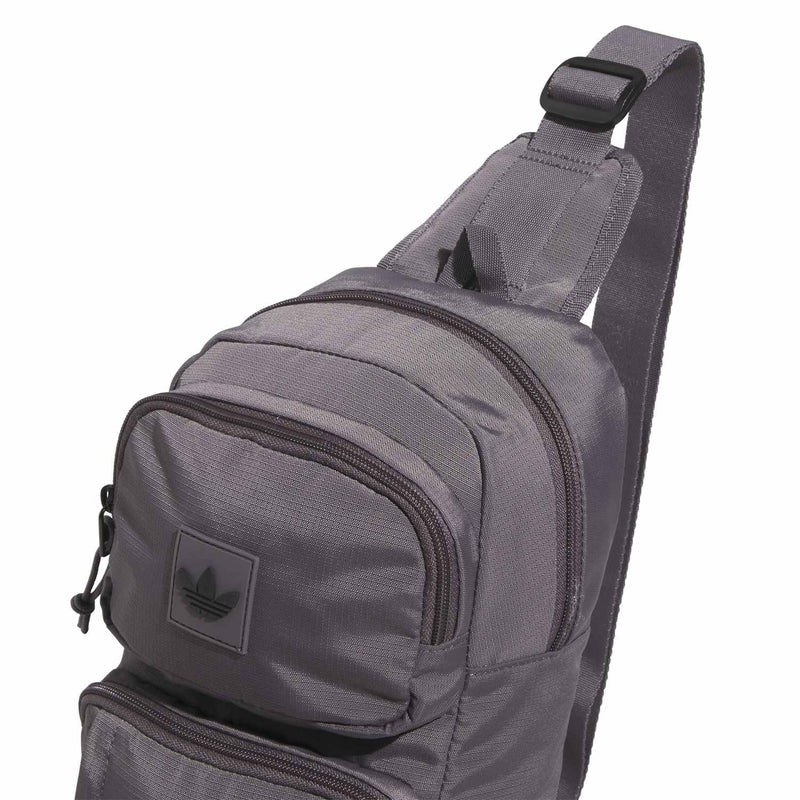 Grey sling bag with padded shoulder strap and front zip pocket