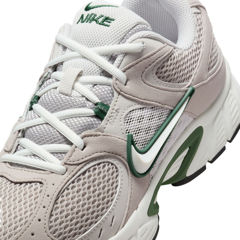 Close-up of light gray mesh sneaker with green swoosh and white lace-up