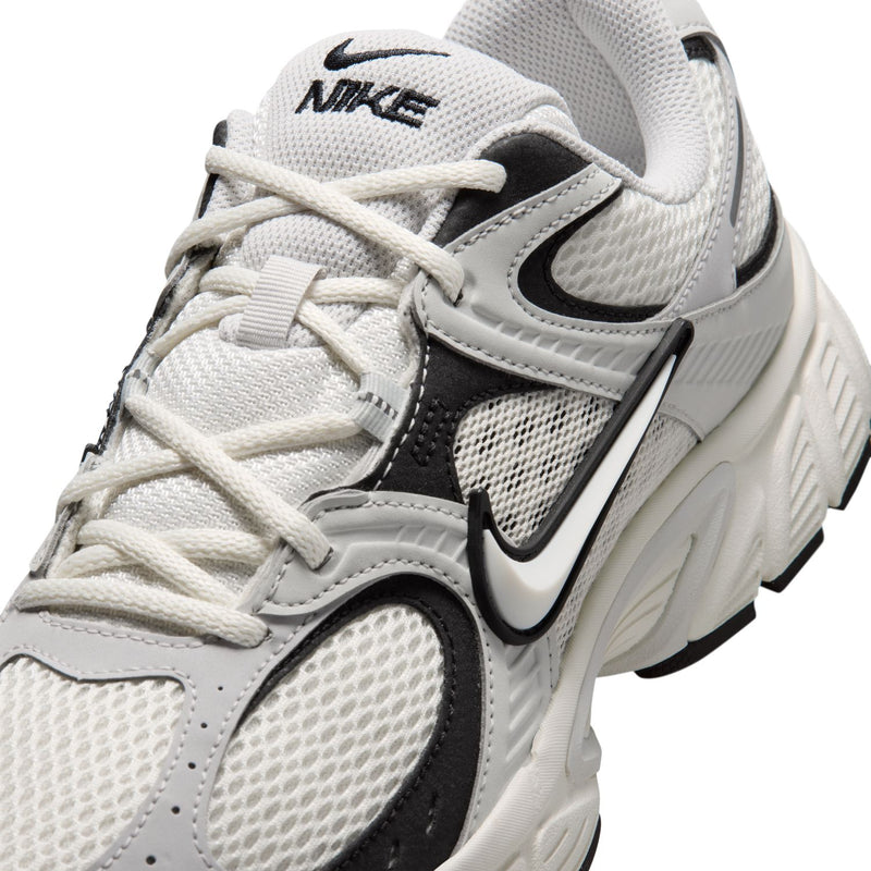 Men's running shoe close-up, light gray mesh upper with black swoosh and off-white laces