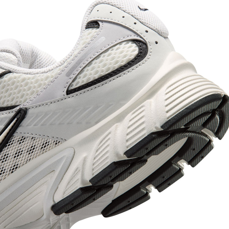 Men's running shoe side close-up with light gray upper and black-and-white tread