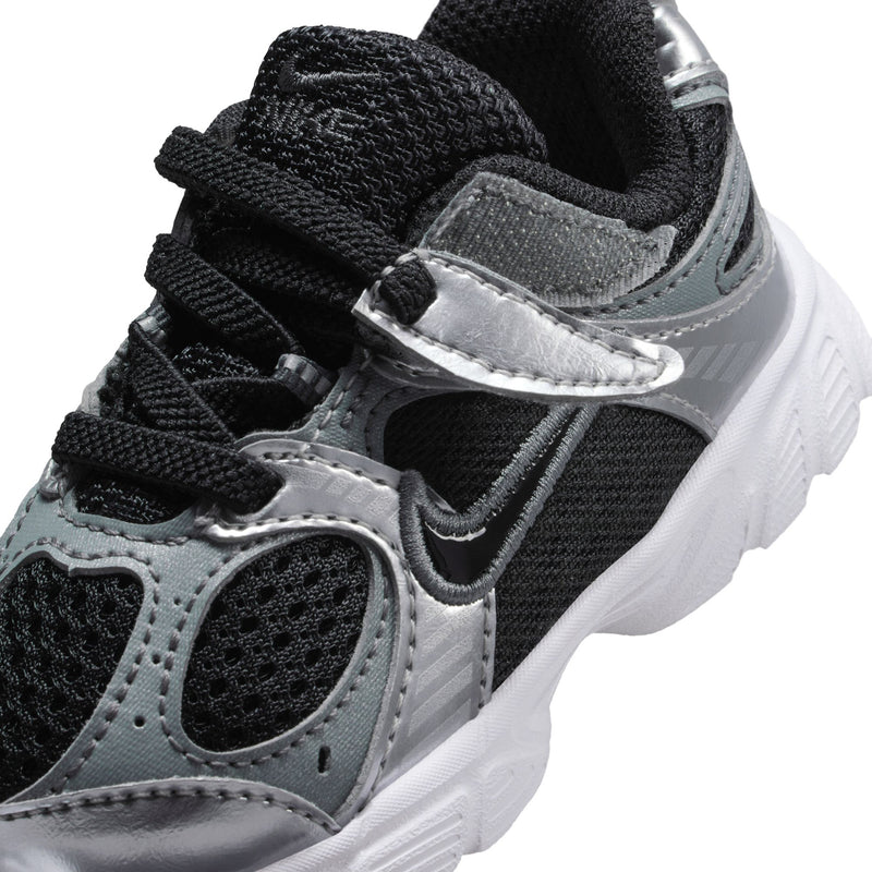 Toddler sneaker close-up with black laces, silver accents, and grippy white midsole