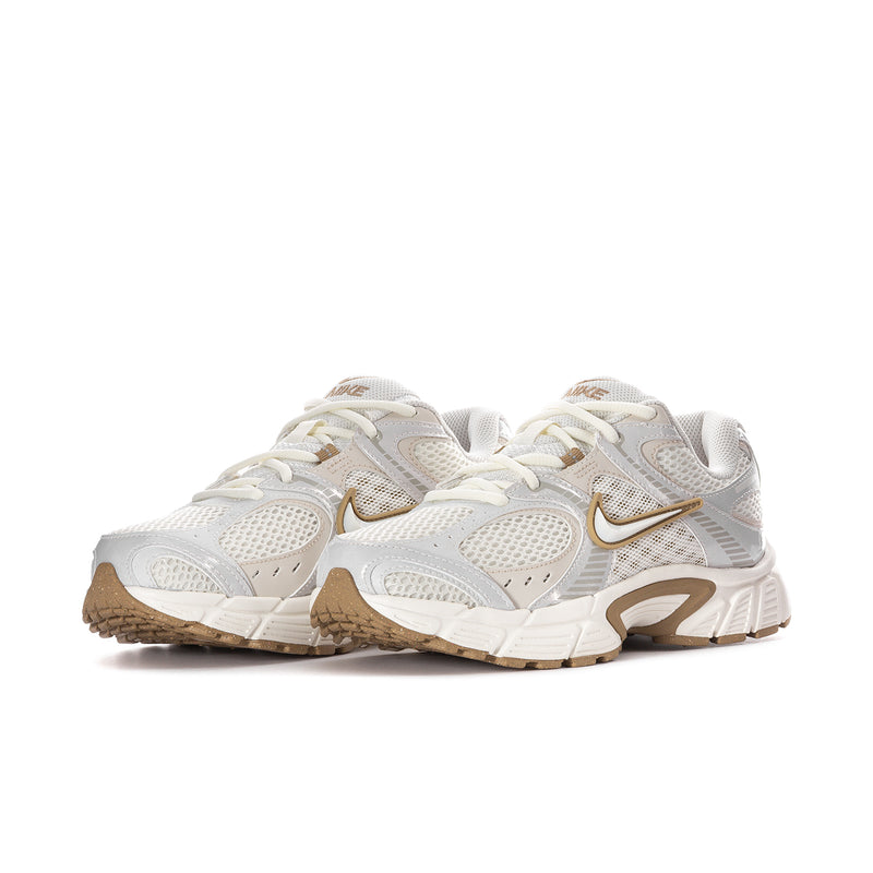 Women’s athletic sneaker side view in white with tan sole and gold swoosh