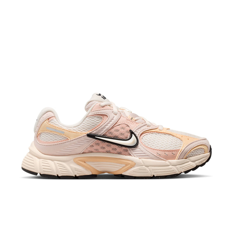 Women's running shoes in pale pink with black Nike Swoosh and tan accents