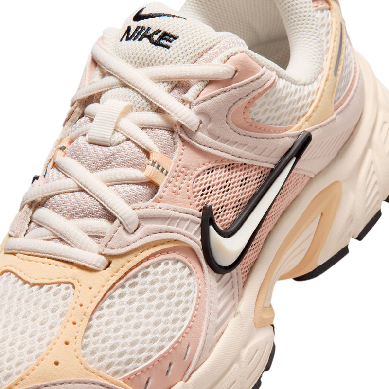 Close-up of pale pink mesh running shoe with black Nike Swoosh and lace detail