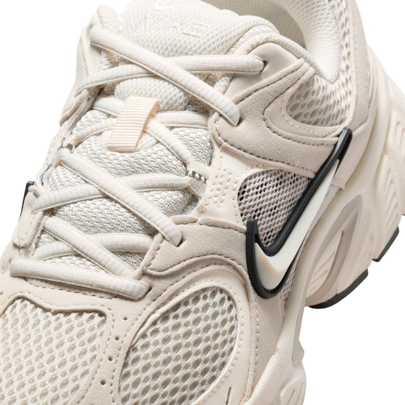 Womens cream running sneaker close-up with mesh panels, laces, and Nike Swoosh