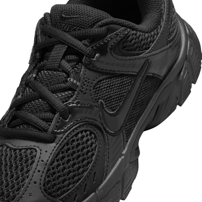 Close-up of youth black shoe upper: mesh panels, stitched overlays, and laces.