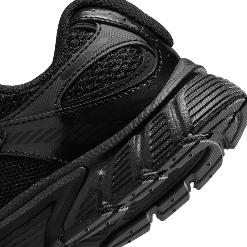 Close-up of youth black sneaker side with ribbed texture and outsole tread details.