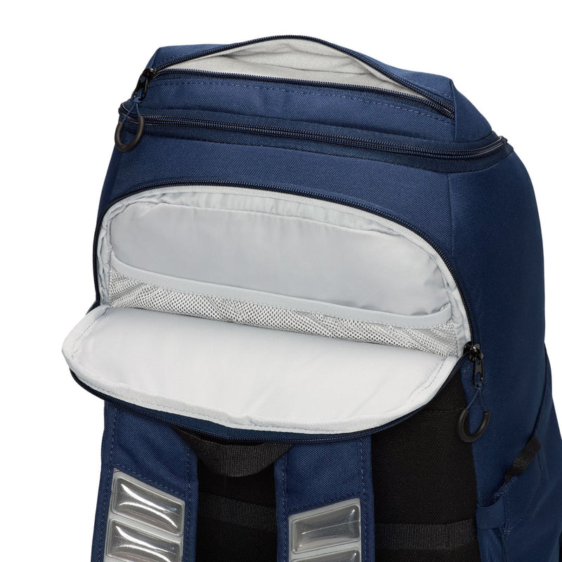 Navy backpack with open front pocket, white pouch lining, and two silver patch tabs