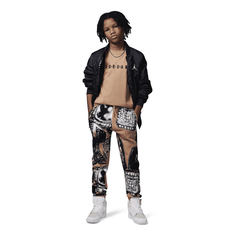 Tan youth crewneck T-shirt with Jordan wordmark, worn with patterned pants