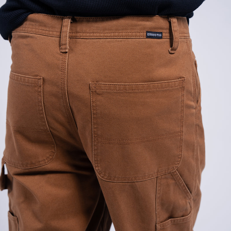 Brown work pants close-up: waistband logo patch and front pocket